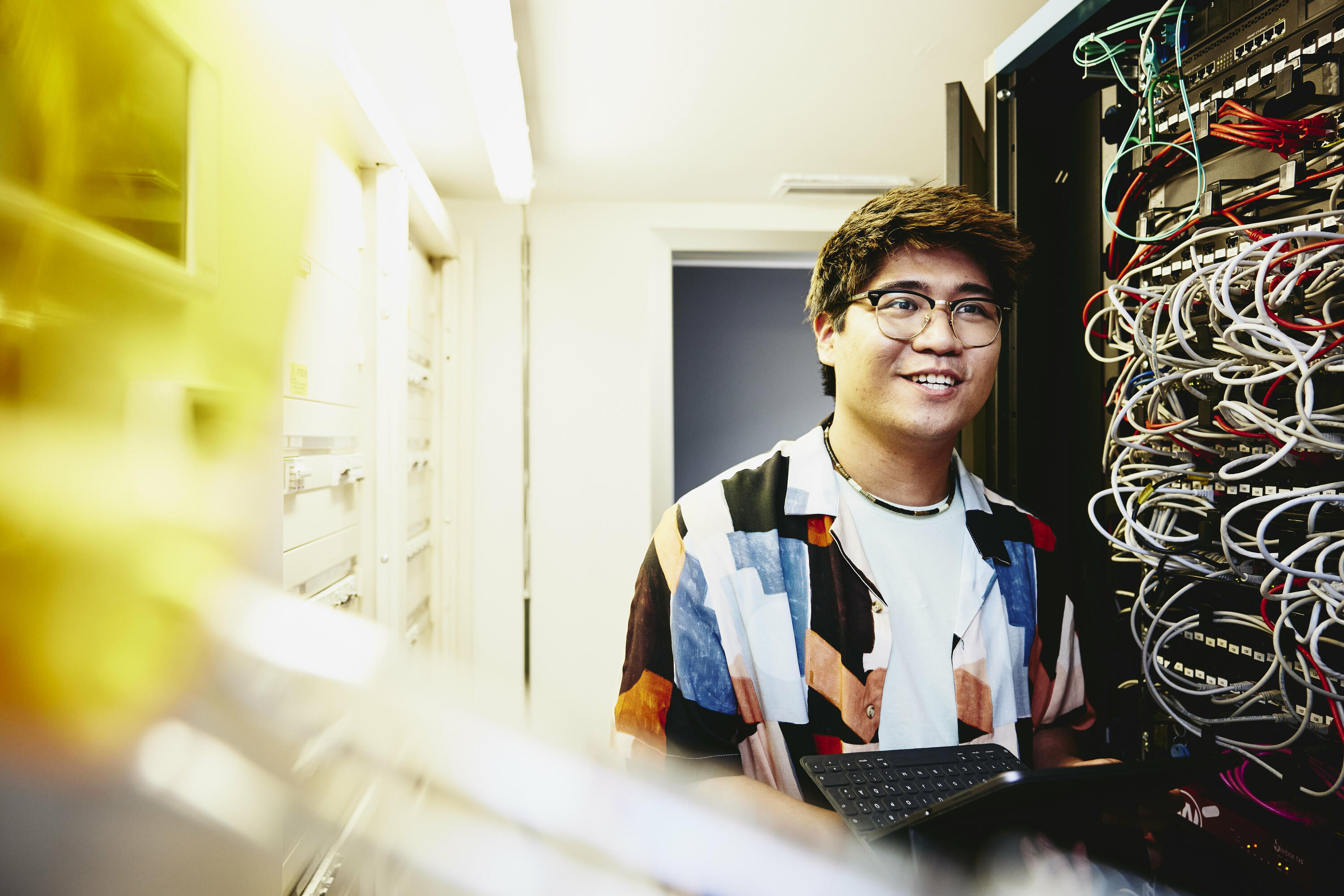 Smiling man holding an tablet standing in a servers room. Smiling man holding an tablet standing in a servers room.