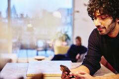 Mand i privat hjem med mobiltelefon