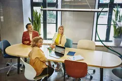Group of people sitting at a oval table, having a meeting