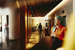 Smiling woman receptionist standing next to hotel reception desk.