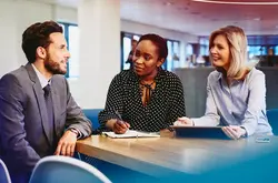 Business male and female having a meeting, smiling and taking notes in an office.