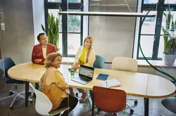 Group of people sitting at a oval table, having a meeting