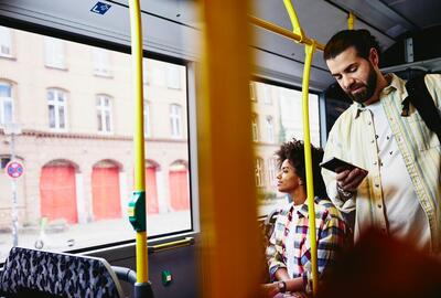 Mand i bus, som kigger på sin telefon