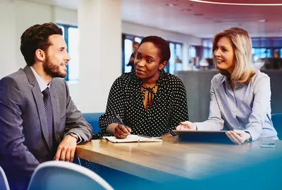 Business male and female having a meeting, smiling and taking notes in an office.