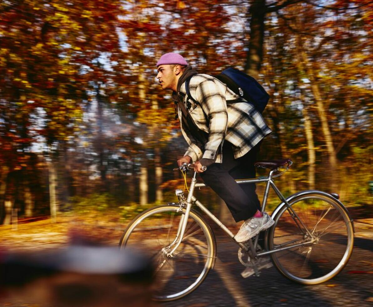 Mand på cykel med rygsæk og lilla hue