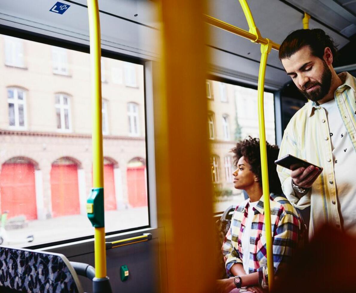 Mand i bus, som kigger på sin telefon