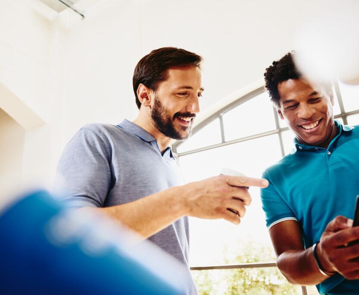 two smiling colleagues looking at a phone