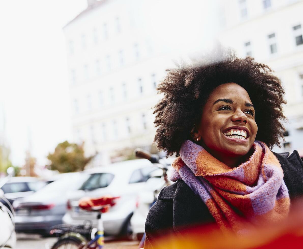 Smiling woman looking up while walking outside.