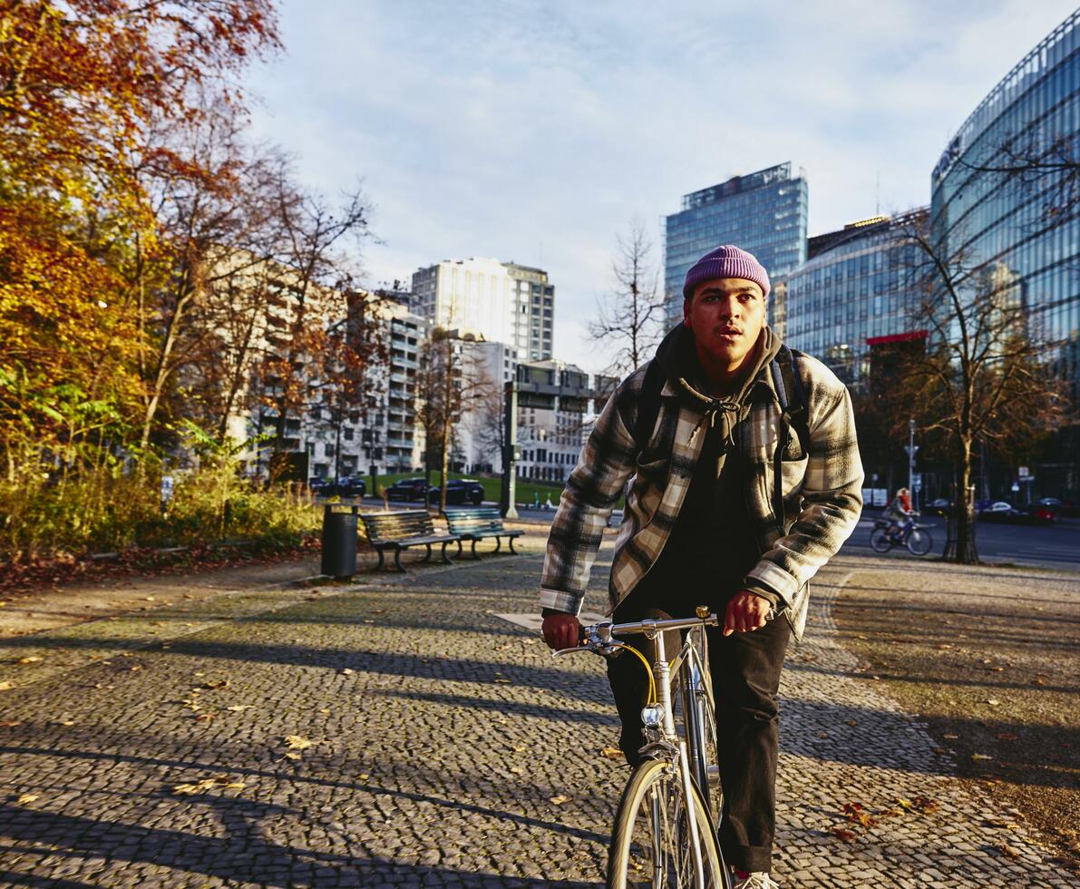 Cycling man, autumn trees and office buildings on the background.