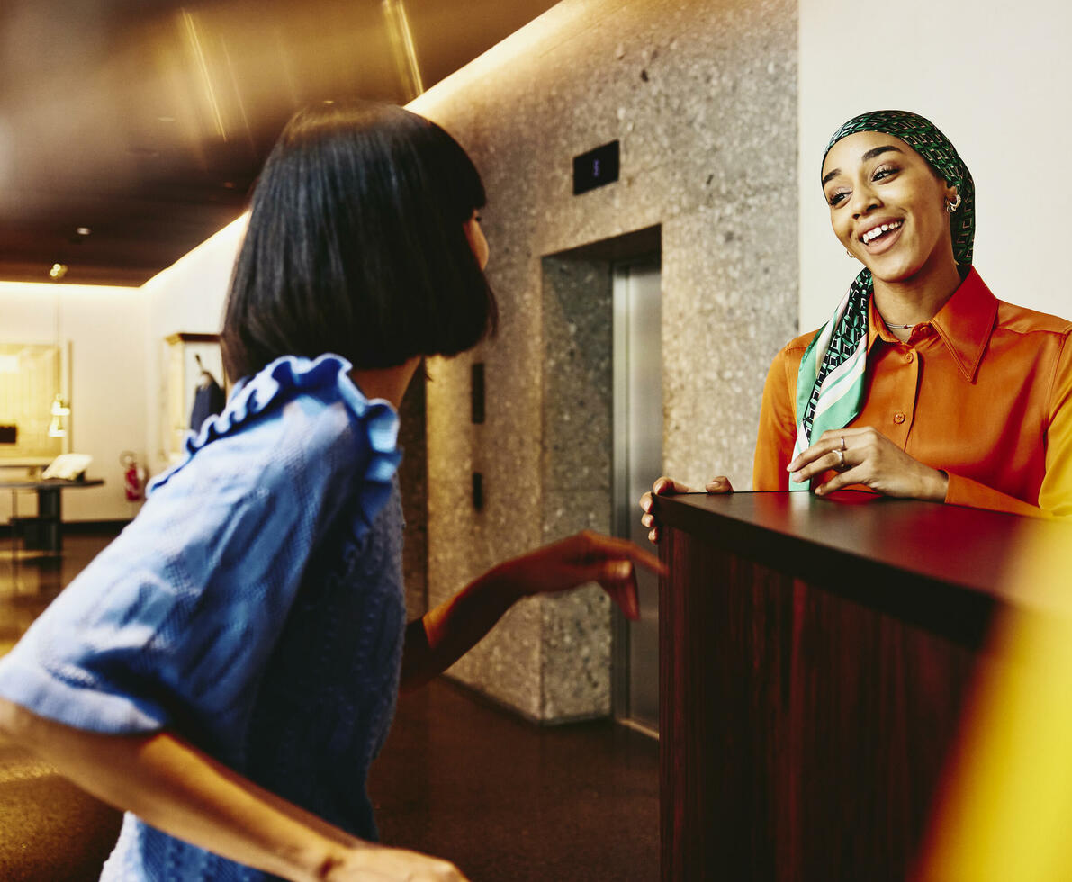 Smiling hotel receptionist helping a guest. 