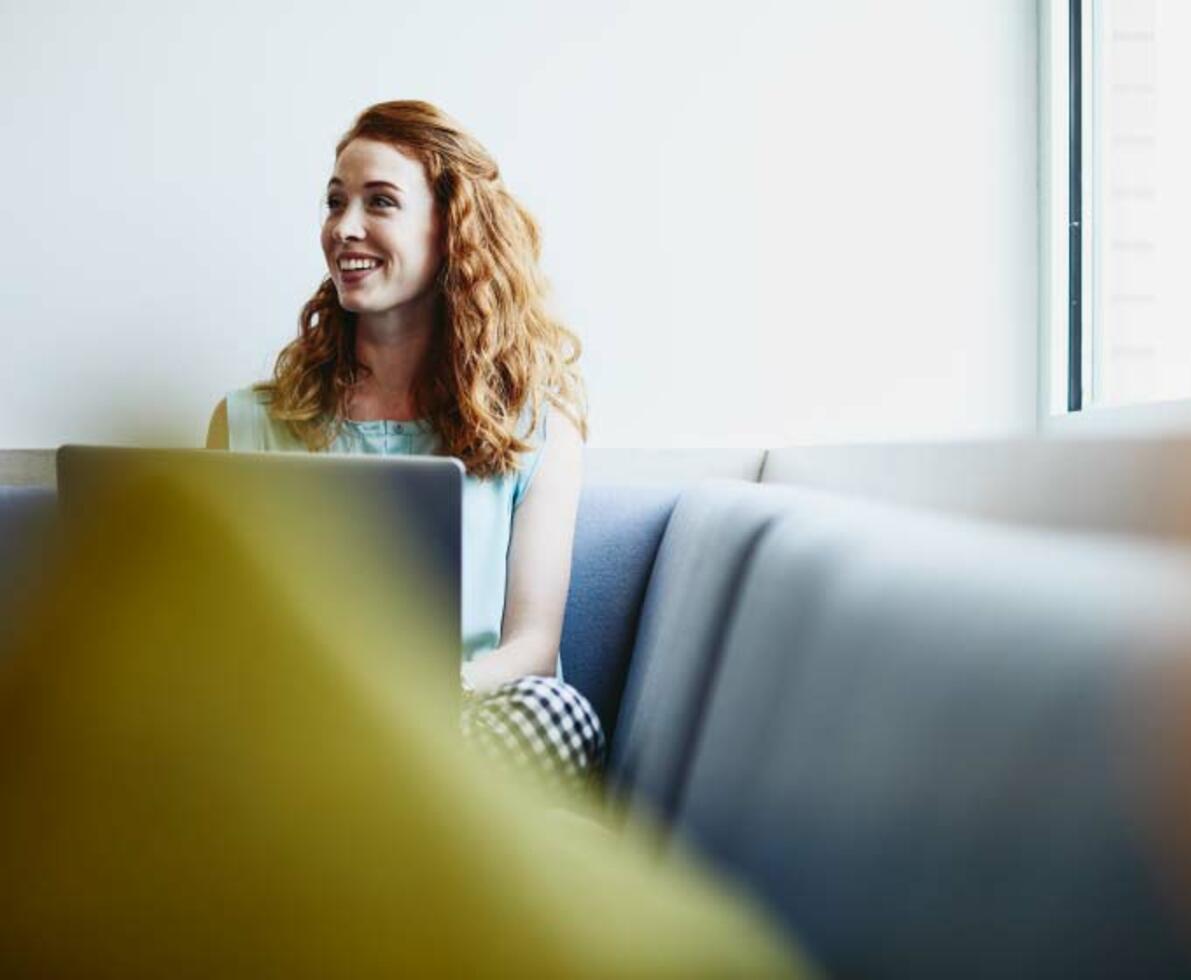 image of a woman sitting smiling on her laptop