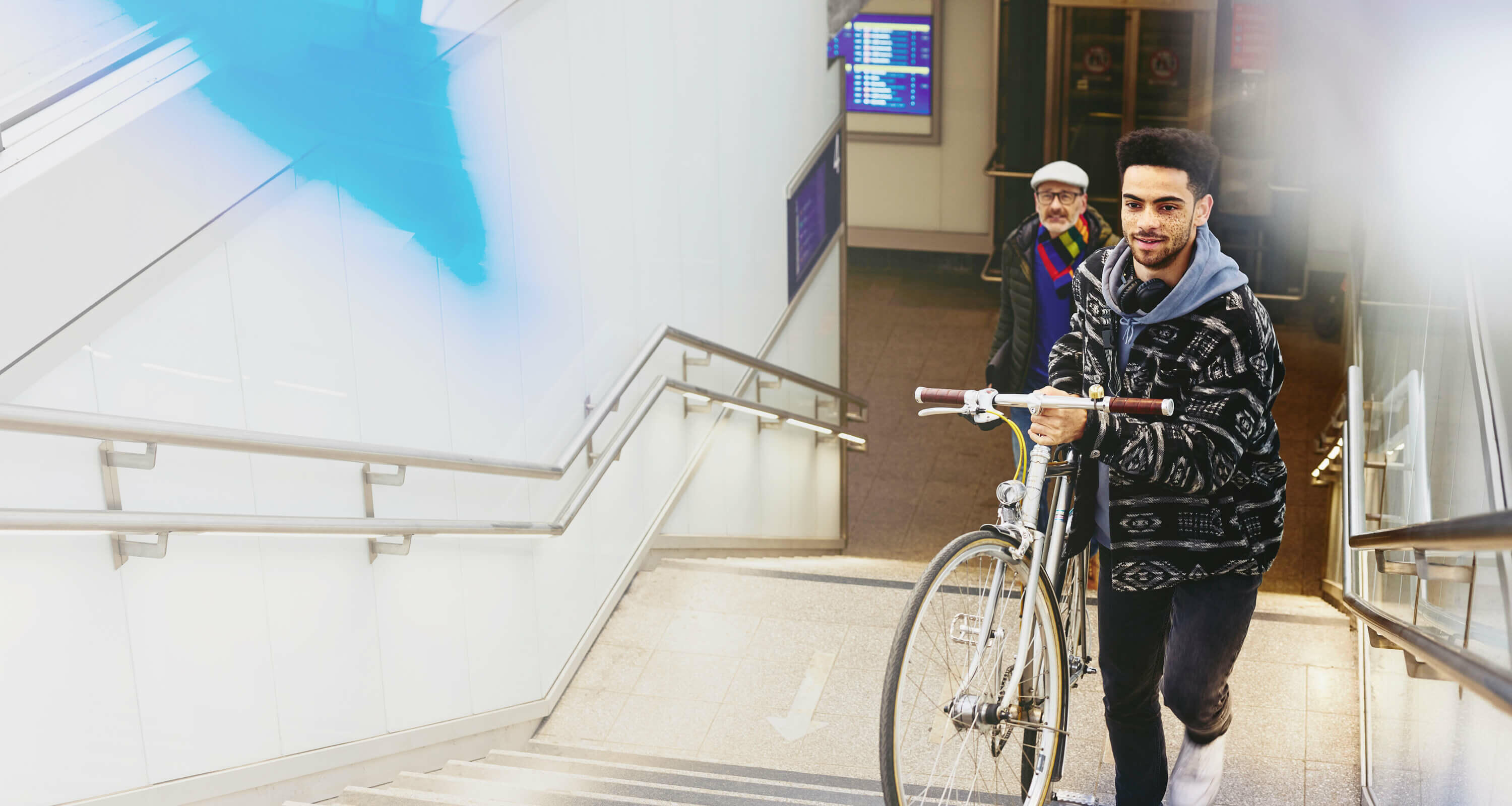 Ung mand med cykel på vej op ad trapper ved togstation