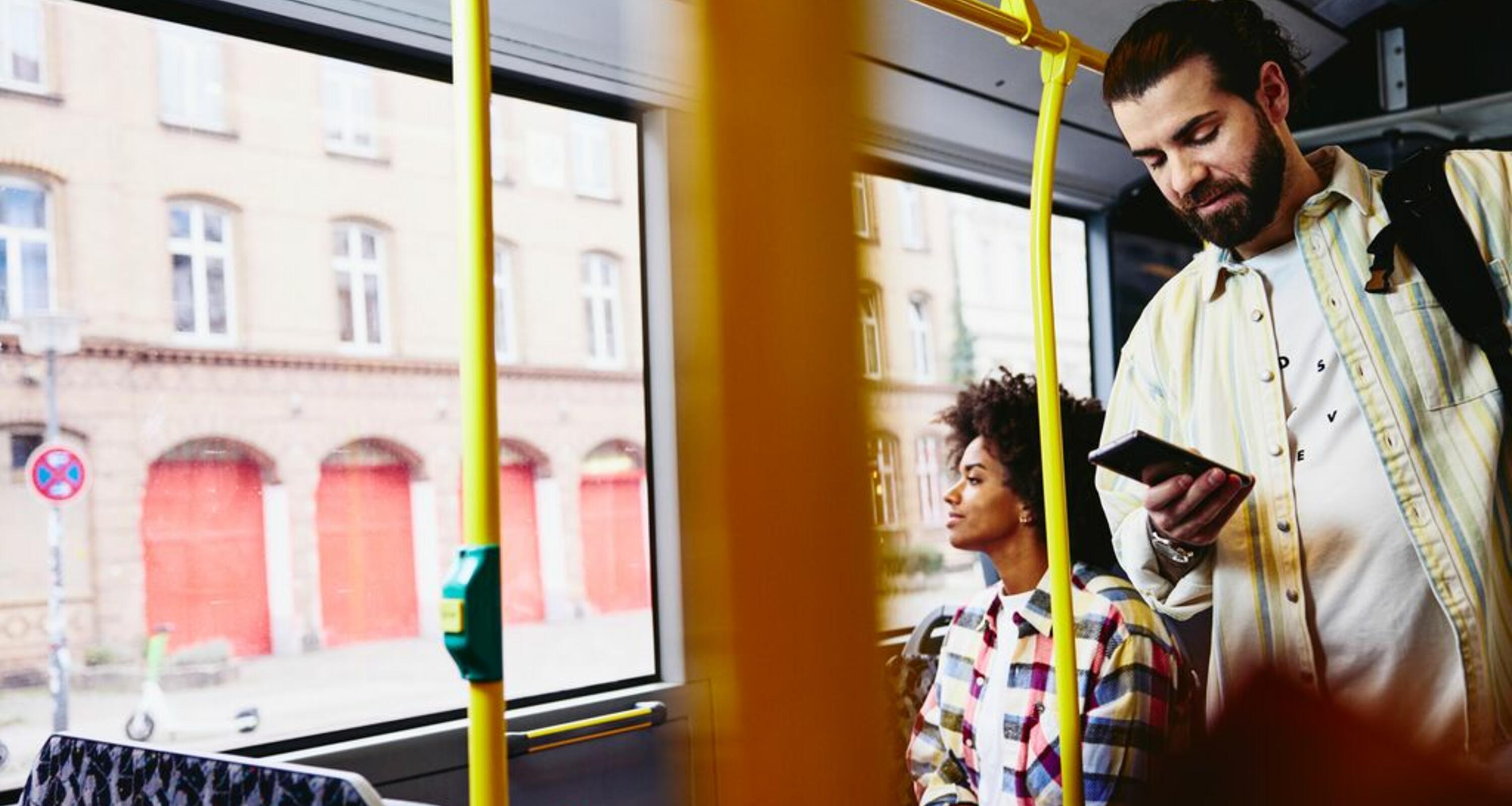 Mand i bus, som kigger på sin telefon