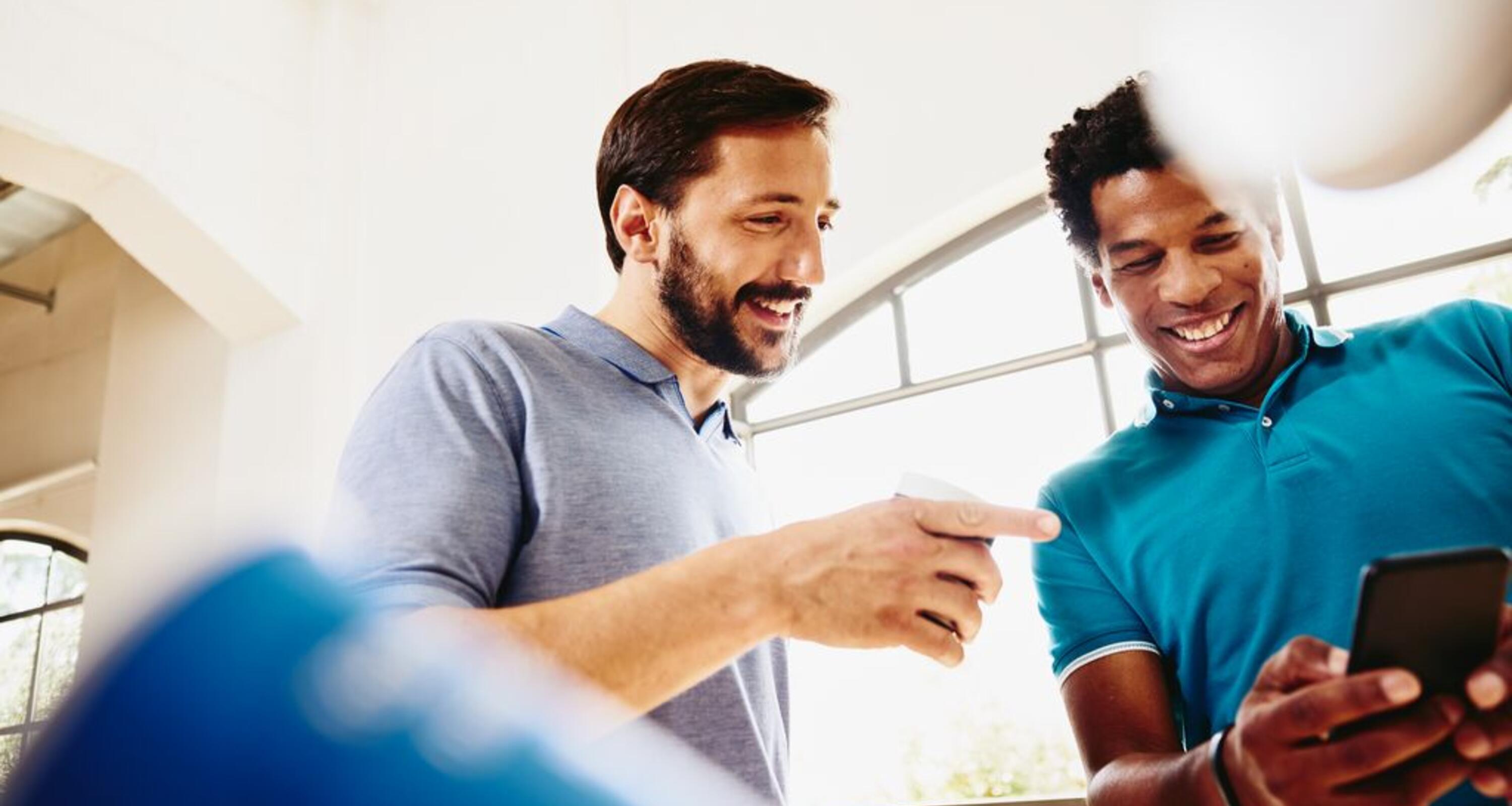 two smiling colleagues looking at a phone